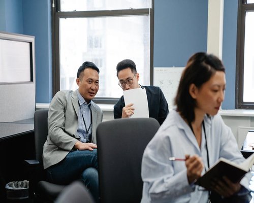 Editorial team members discussing notes in an airy room